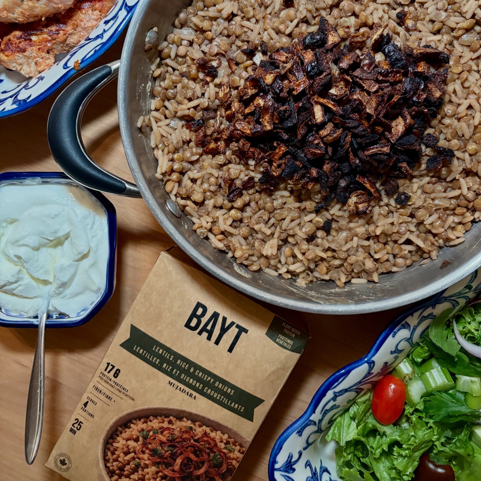 Bayt mujadara in a pan — lentils, rice and crispy onions, with the BAYT carton